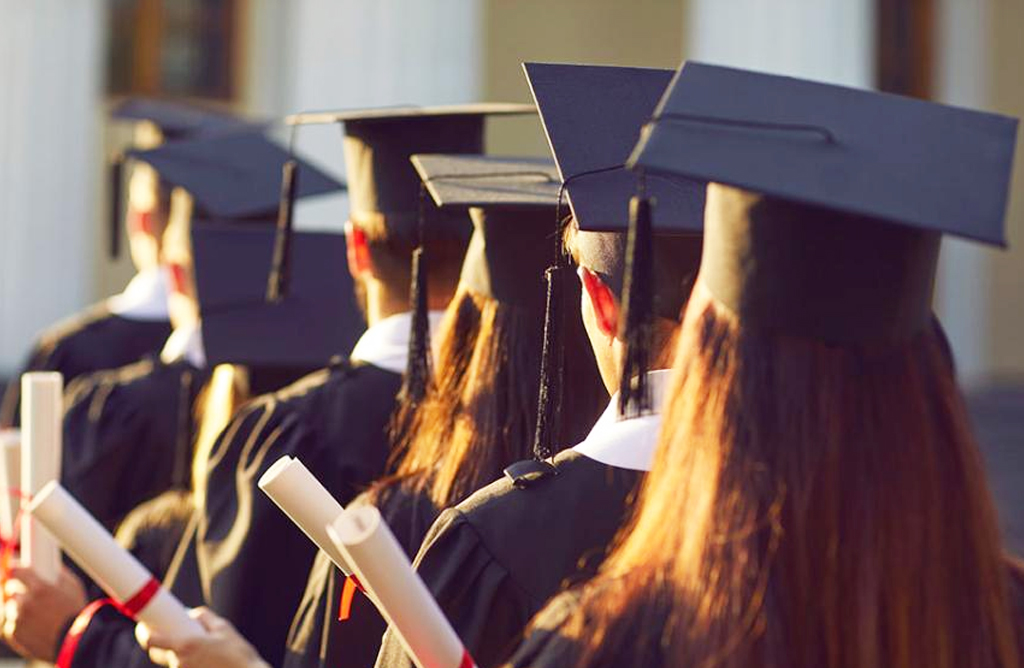 Students in Graduation Gowns Holding Diplomas at Ceremony