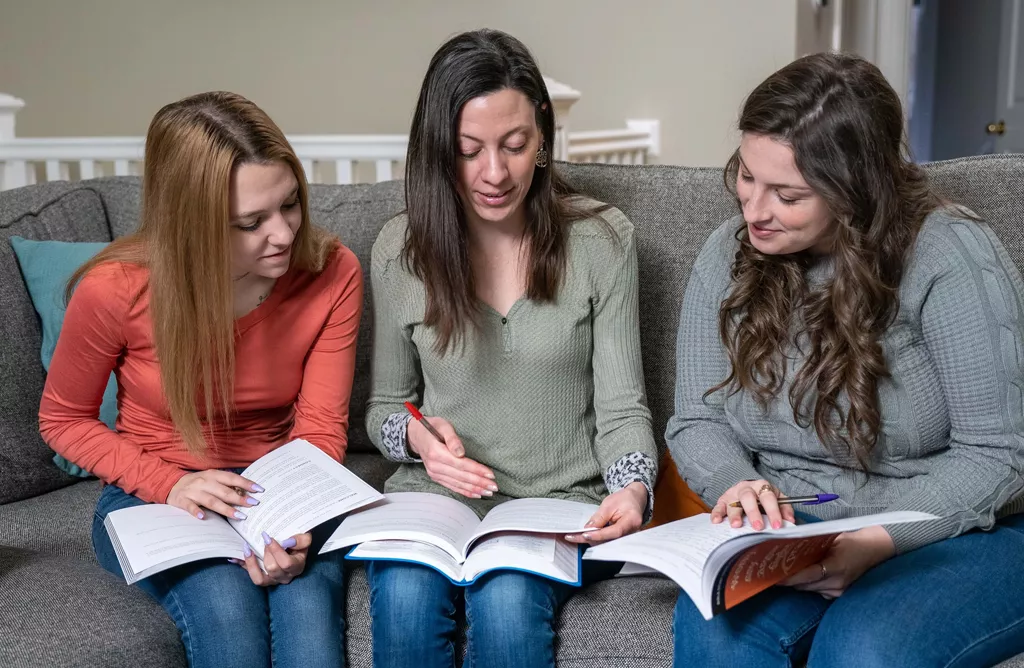 Three Girls Studying and Discussing Books at Home