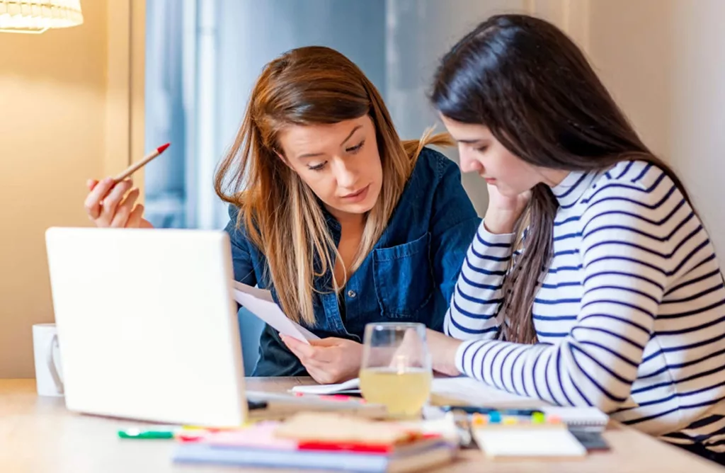 Two Women Studying Together with a Laptop and Documents