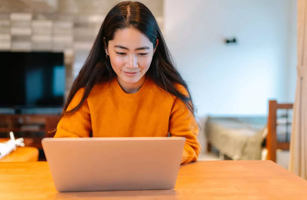 Young Woman Studying on Laptop in a Cozy Home Workspace