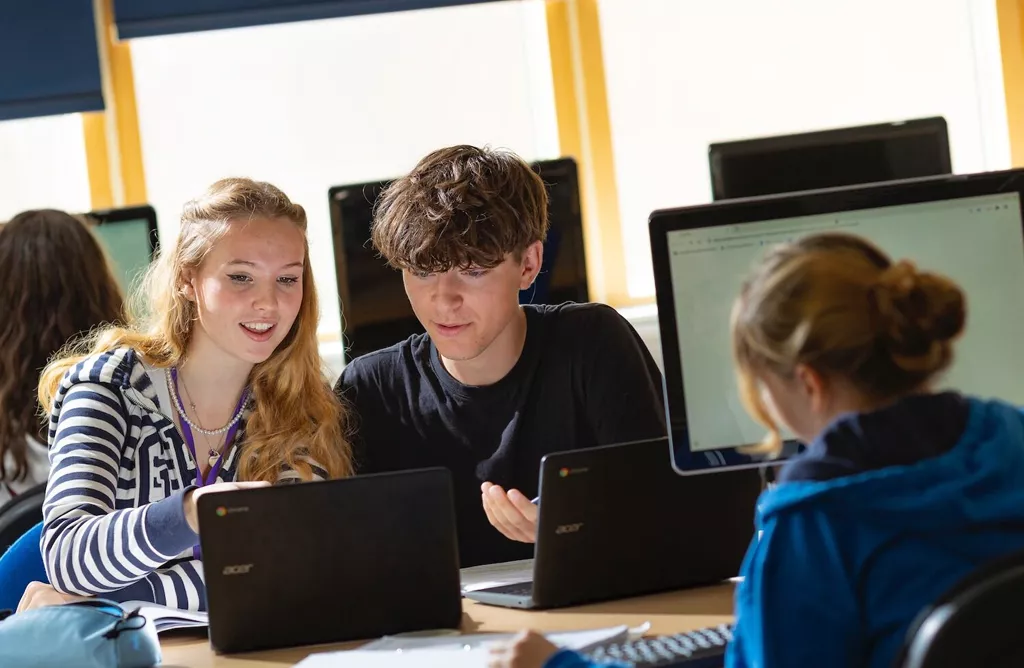International Students Collaborating on Laptops in Classroom